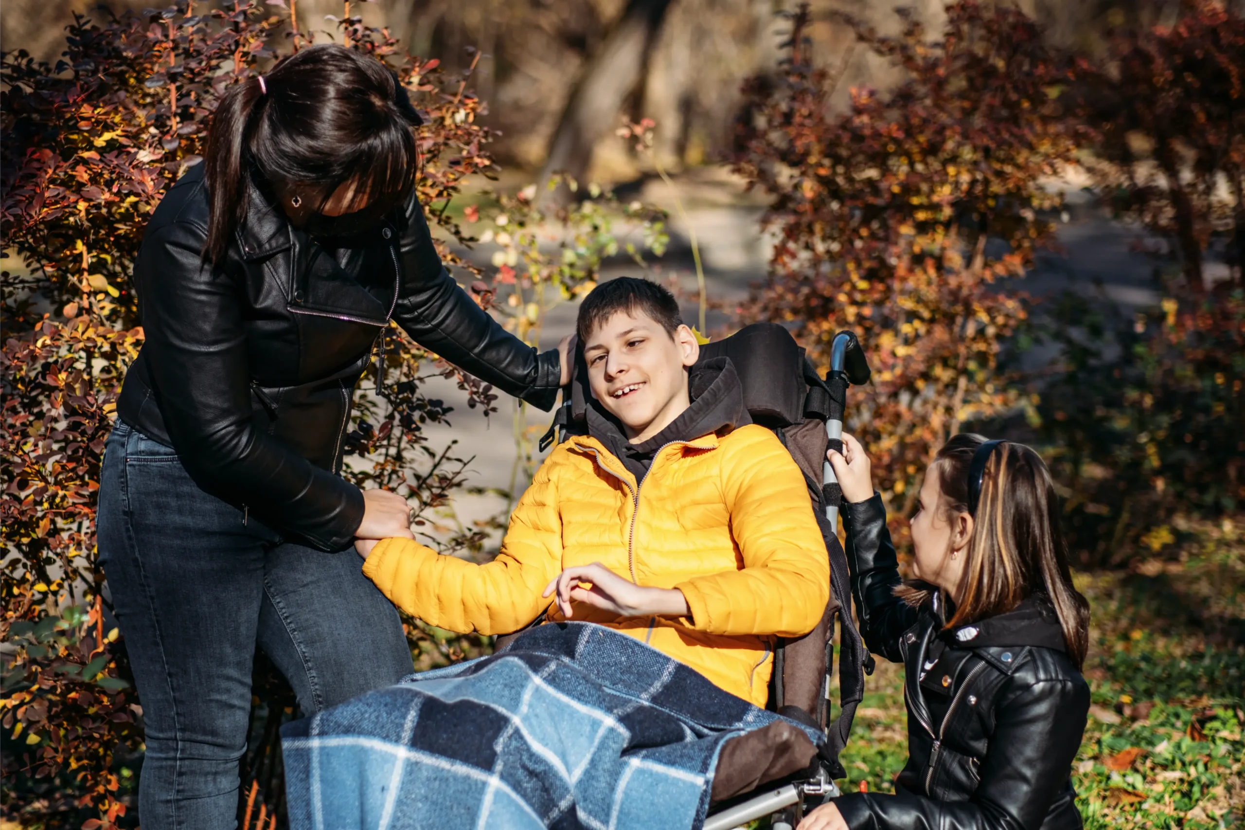 Teen in wheelchair with family in an autumn park